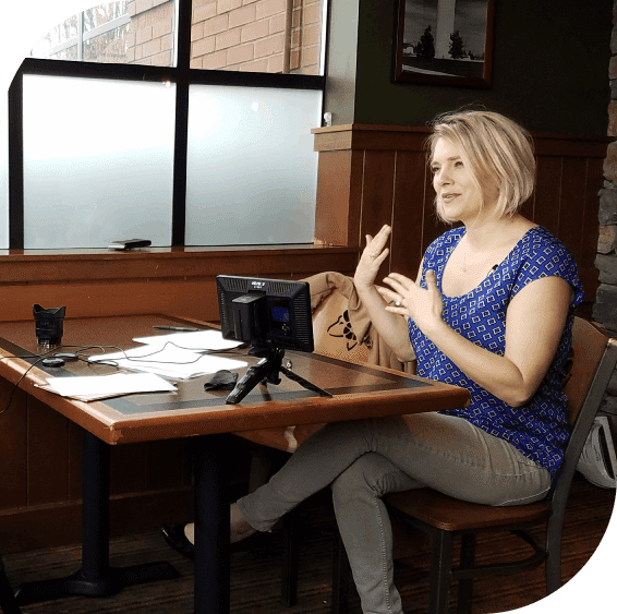 A woman sitting at a table with a camera.