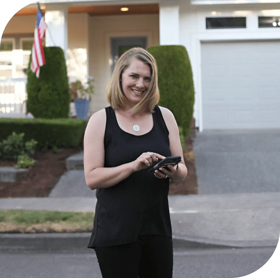 A woman standing on the street holding her cell phone.