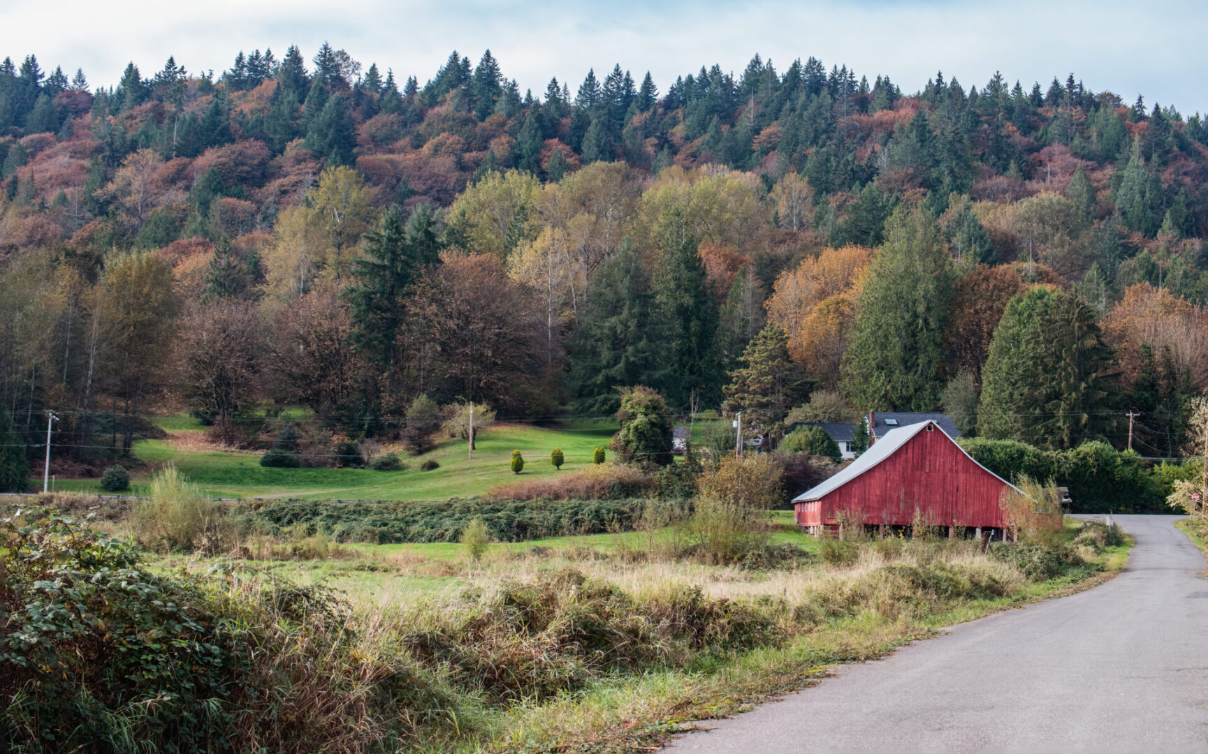 A red barn sits in the middle of a field.