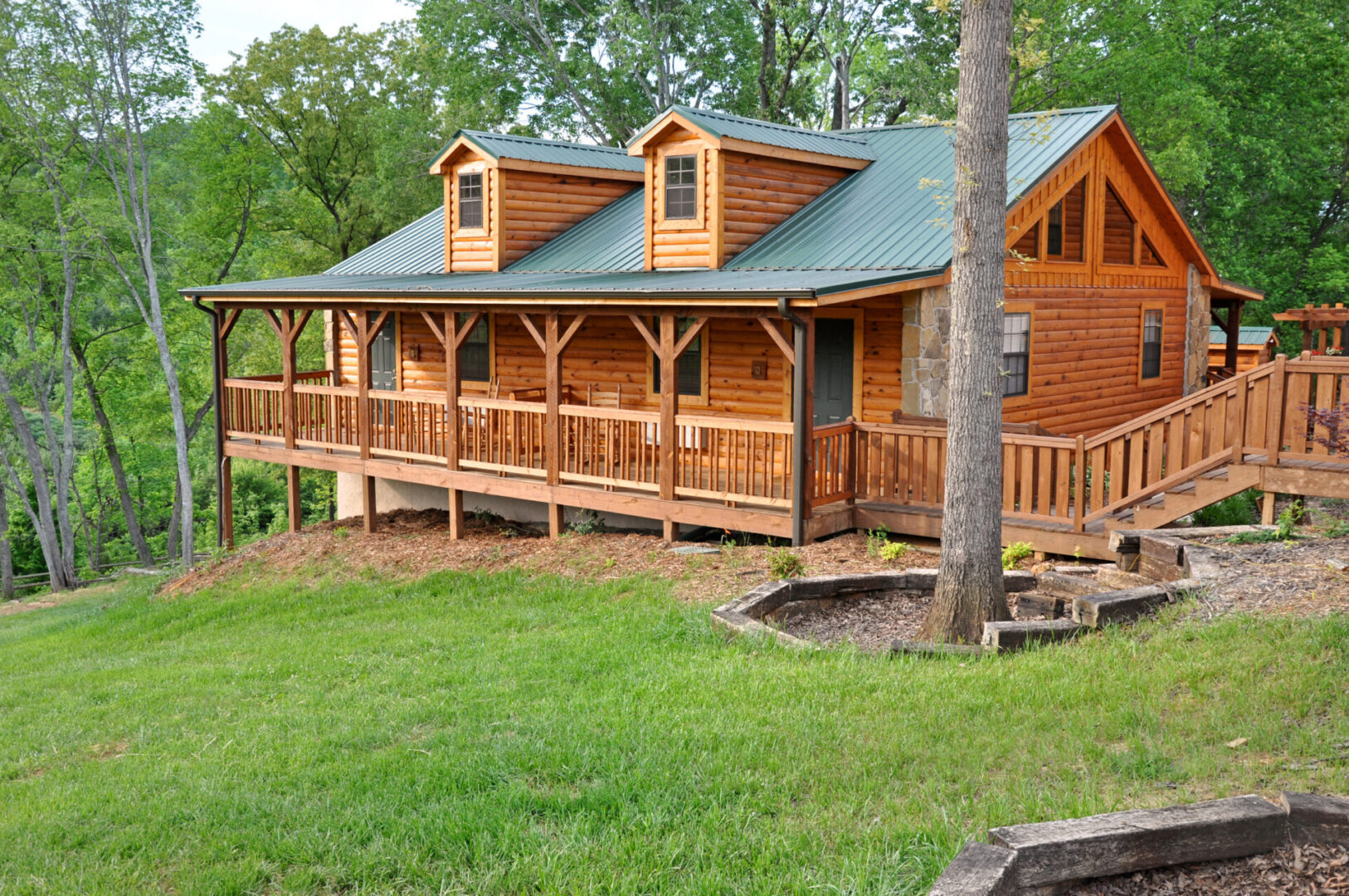 A log cabin with a porch and trees in the background.