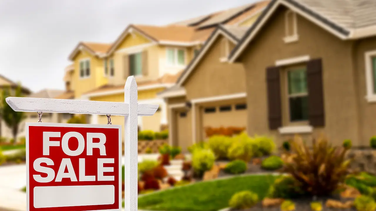 A red sign sitting in front of some houses